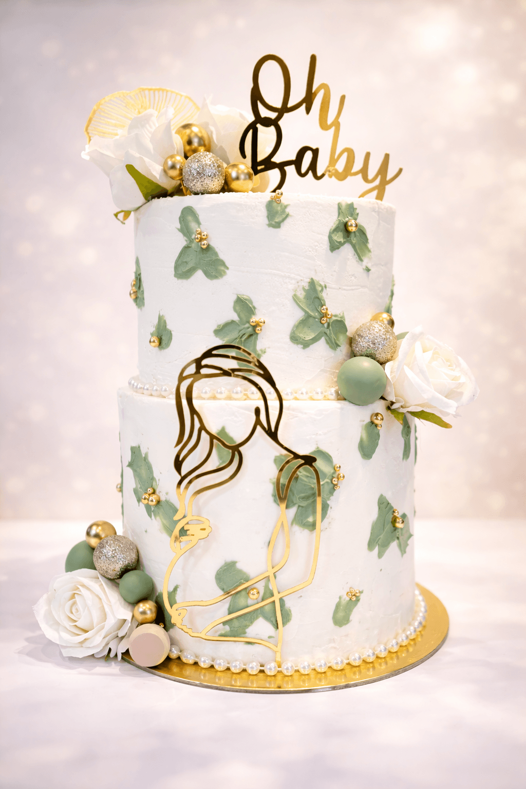 Two-tier white baby shower cake with sage butterfly details, gold accents, and an Oh Baby topper, made by Cakes by Ashni in New Jersey